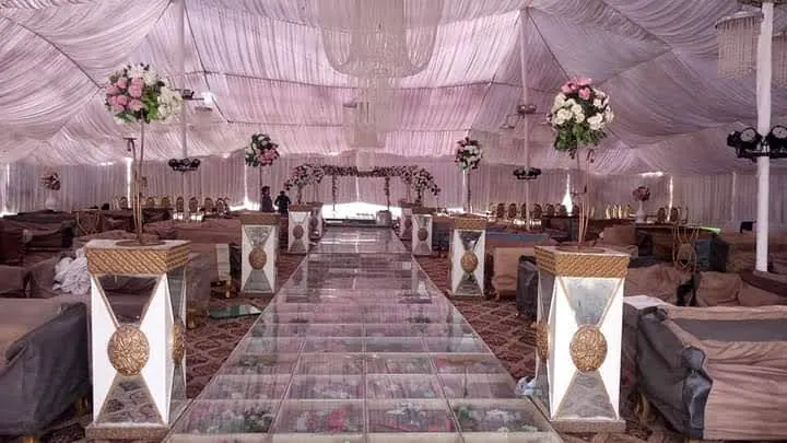 A glass aisle lined with white flowers inside a white marquee