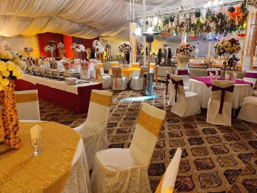Guests at a buffet line under a marquee