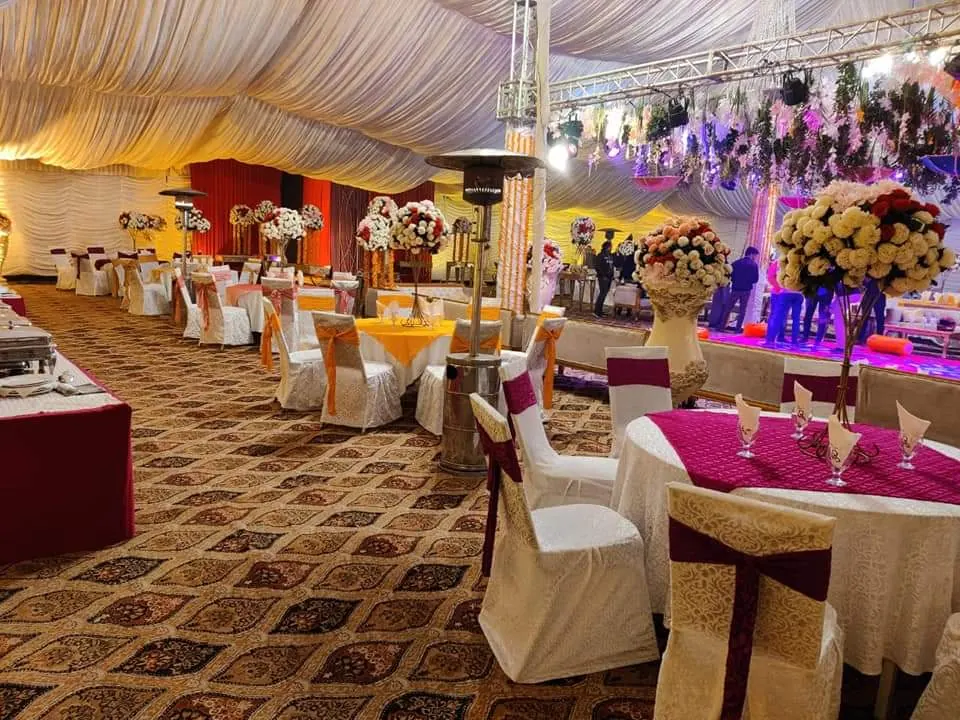 A buffet table with bright flowers under a coloured canopy
