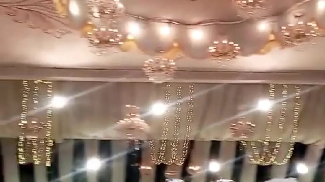 Chandeliers hanging from the draped ceiling of a wedding marquee