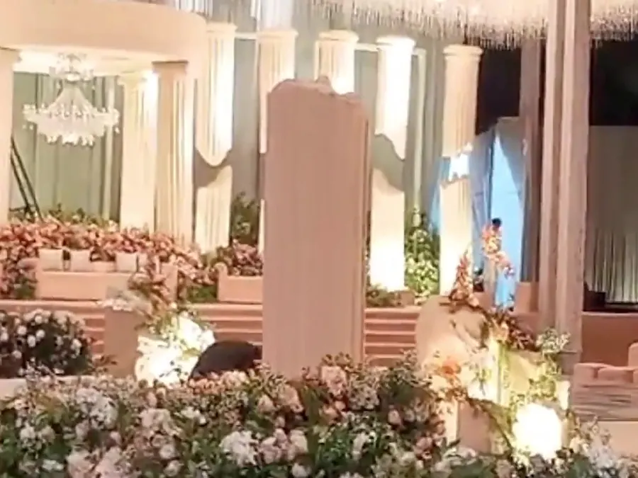 A wedding stage dressed with white and pink flowers and a lit floral aisle