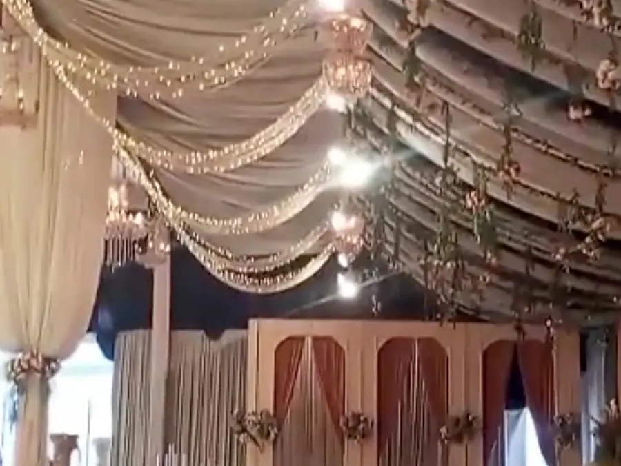 Inside a white marquee with a pleated draped ceiling and fairy lights